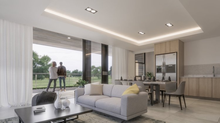 Modern living room with light-colored sofa, dining table, kitchen with stainless steel appliances, large windows showing outdoors with two people standing on the balcony.